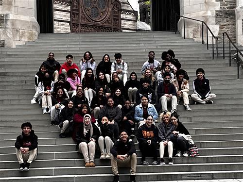 Large group of students sitting on stone staircase.